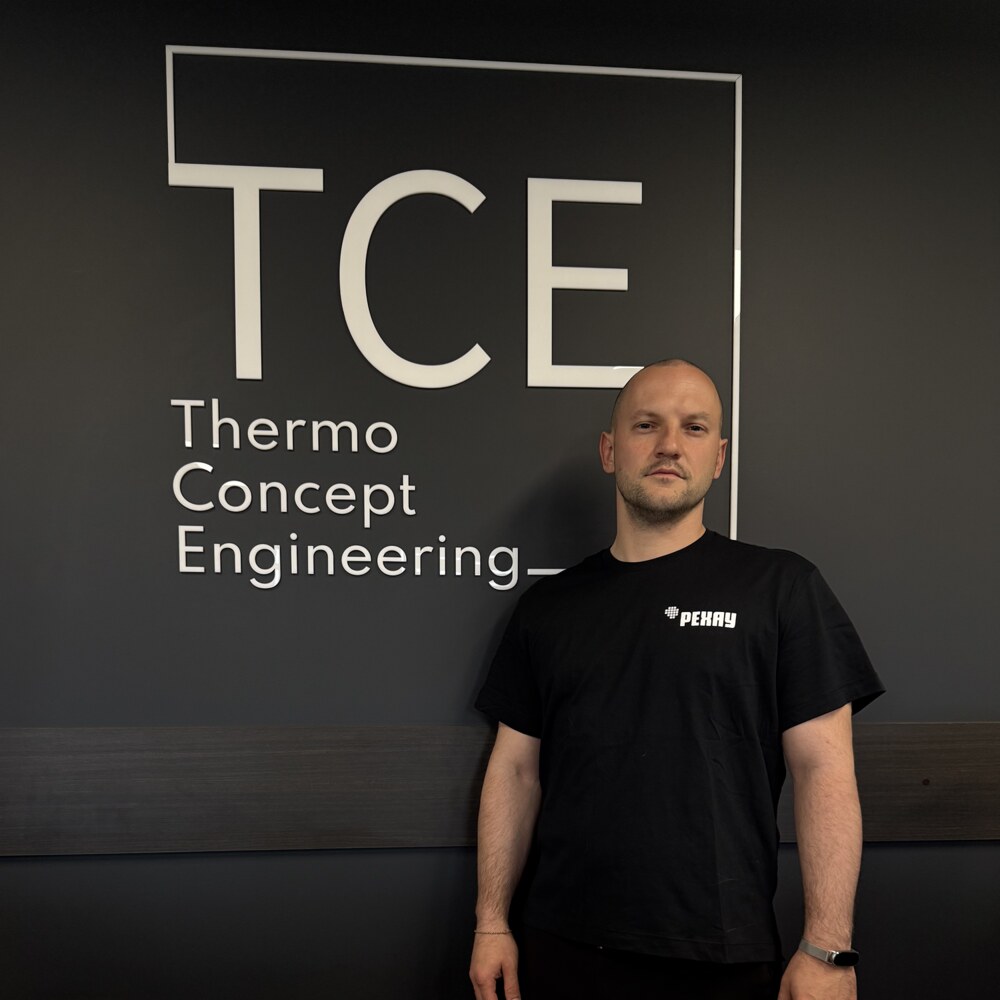 Сотрудник TCE у логотипа компании в офисе